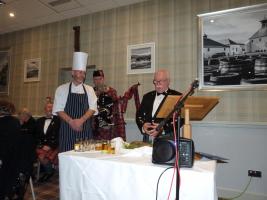 Member Martyn O'Reilly gives the address to the Haggis alongside the piper